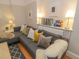 A living room with a sofa and books on a shelf at Bwthyn Morse in Llanfair