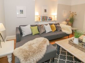 A living room with a sofa, bookshelves, and a lamp at Bwthyn Morse in Llanfair