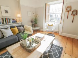 A living room with a sofa and books on a shelf at Bwthyn Morse in Llanfair