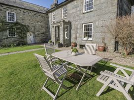 A garden with a table and chairs in front of a stone building at Bwthyn Morse Llanfair