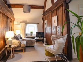 A living room with a sofa, lamp, and television at Bwthyn Canol in Llanfair