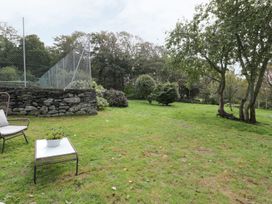 A garden area with a stone wall and seating at Bwthyn Canol in Llanfair