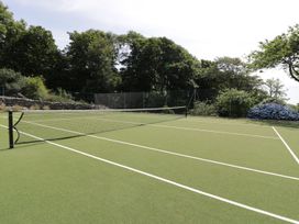 A tennis court with net and greenery at Bwthyn Canol in Llanfair