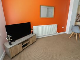 A living room with a television and a mirror at Curwen Apartment in Workington