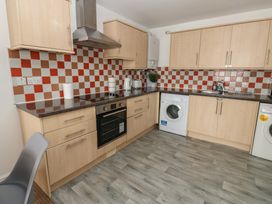 A kitchen with cabinets, oven, washing machine and kettle at Curwen Apartment in Workington