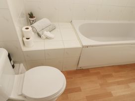 A bathroom with a toilet and bathtub at Curwen Apartment in Workington