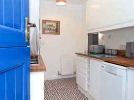A kitchen with cabinets and appliances at Kenny Cottage in Dawlish