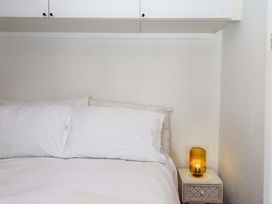 A bedroom with a bed, pillows, lamp, and nightstand at Kenny Cottage in Dawlish