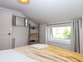 A bedroom with a bed and shelves at Kenny Cottage in Dawlish