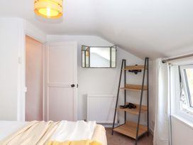A bedroom with a mirror and shelf at Kenny Cottage in Dawlish