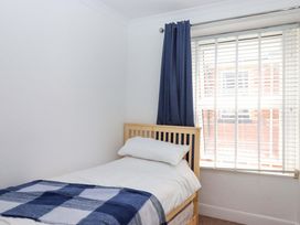 A bedroom with a bed and window at Kenny Cottage in Dawlish