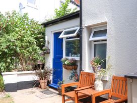 An outdoor area with a blue door, window, plants, and seating at Kenny Cottage in Dawlish