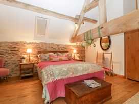 A bedroom with a bed, nightstand, and wooden beams at The Art House in Leominster