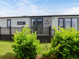A mobile home with a deck and bushes at Hazelnut Lodge in Chipping Norton