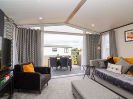 A living room with a sofa and television at Hazelnut Lodge in Chipping Norton
