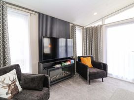 A living room with a television and armchairs at Hazelnut Lodge in Chipping Norton
