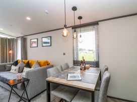 A living room with a sofa and dining area at Hazelnut Lodge in Chipping Norton