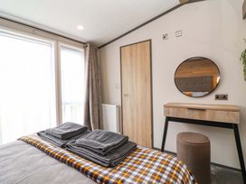 A bedroom with a bed and a dressing table at Hazelnut Lodge in Chipping Norton
