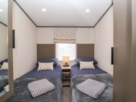 A bedroom with two beds and a bedside table at Hazelnut Lodge in Chipping Norton