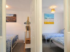 A bedroom with two beds and artwork on the wall at 8 Hillside Bude