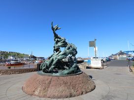 A statue of fish near boats at the marina in Whitehaven