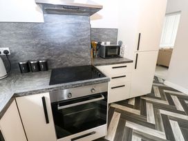 A kitchen with oven, cooktop, microwave, and cabinets at Lowther Suite Whitehaven