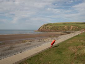 A beach with a cliff and walkway at Lowther Suite in Whitehaven
