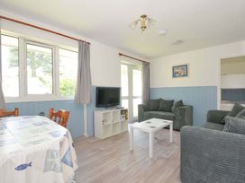 A living room with a table and chairs and a tv at 4 Rosecraddoc Lodge Holiday Bungalows in Liskeard