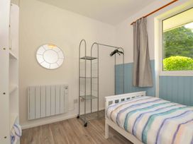 A bedroom with a bed and a mirror at 4 Rosecraddoc Lodge Holiday Bungalows in Liskeard