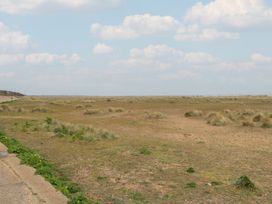 A grassy area with a sandy pathway and scattered clouds at No. 2 - Seaview in Kessingland