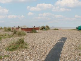 A boat on a pebble beach with grass and a boardwalk at No. 2 - Seaview Kessingland
