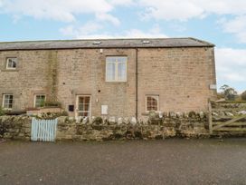 An exterior view of a stone building with windows and a gate at Watermill Cottage in North Charlton