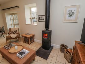 A living room with a stove and seating area at Watermill Cottage in North Charlton