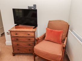 A bedroom with a television on a chest of drawers and an armchair at Watermill Cottage North Charlton