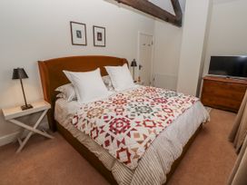 A bedroom with a bed, bedside lamp and television at Watermill Cottage in North Charlton