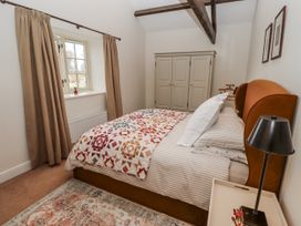 A bedroom with a bed and wardrobe at Watermill Cottage in North Charlton