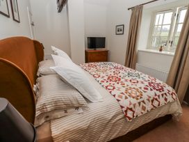 A bedroom with a bed and television at Watermill Cottage in North Charlton