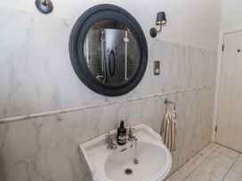 A bathroom with a sink and round mirror at Watermill Cottage in North Charlton