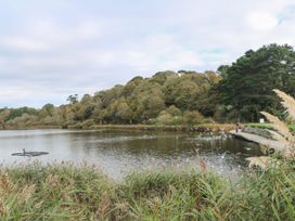 A lake surrounded by trees with birds flying at Trouts Reach in Goldenbank near Budock Water