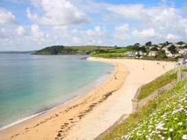 A beach with people walking along the shore at Trouts Reach, Goldenbank near Budock Water