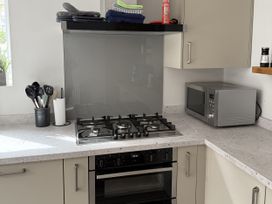 A kitchen with a gas stove and microwave at Mostyn View in West Kirby