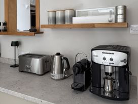 A kitchen countertop with a toaster, kettle, coffee machine, and storage jars at Mostyn View West Kirby