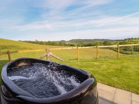 A hot tub with water and a scenic landscape at Defaid Cymreig Oswestry