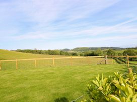 A grassy area enclosed by a fence and hills in the background at Defaid Cymreig in Oswestry