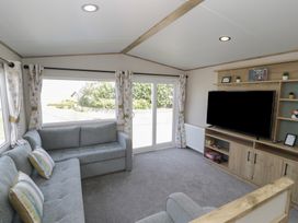 A living room with a sofa and television at Puffin Way Holiday Caravan