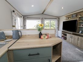 A kitchen area with appliances and a television at Puffin Way Holiday Caravan
