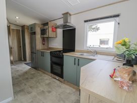 A kitchen with appliances and cabinets at Puffin Way Holiday Caravan 