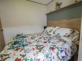 A bedroom with a bed and nightstand at Puffin Way Holiday Caravan