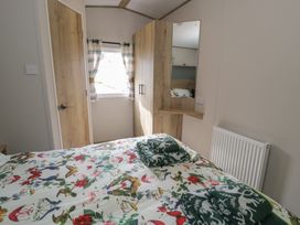 A bedroom with a bed and wardrobe at Puffin Way Holiday Caravan