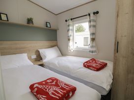 A bedroom with two beds and a window at Puffin Way Holiday Caravan 